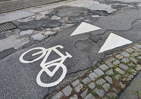 Radfahrer-Markierung auf Schlaglochpiste Radfahrer-Markierung auf Schlaglochpiste