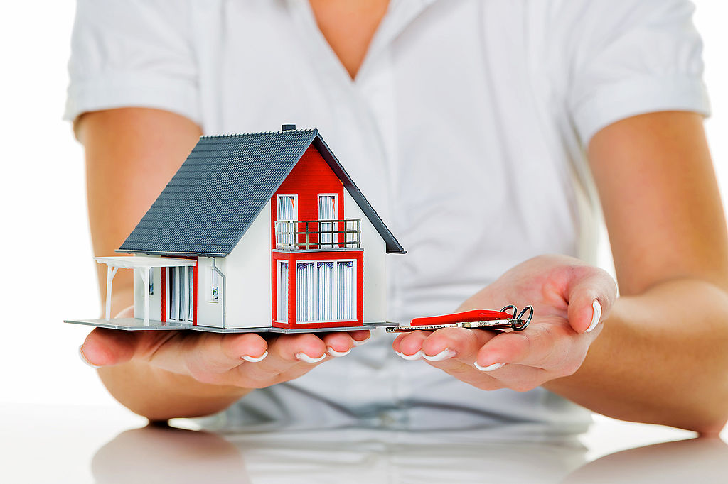 Immobilienmaklerin mit Haus und Schlüßel