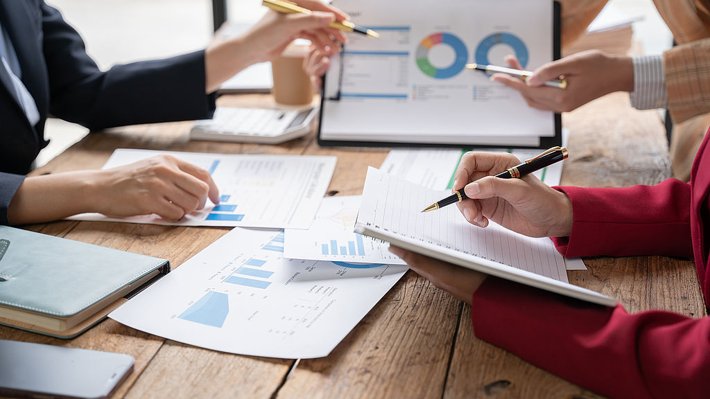 Financial analyst analysis business financial report on digital tablet during discussion at meeting of corporate showing the results of their successful teamwork, business meeting concept, Marketing