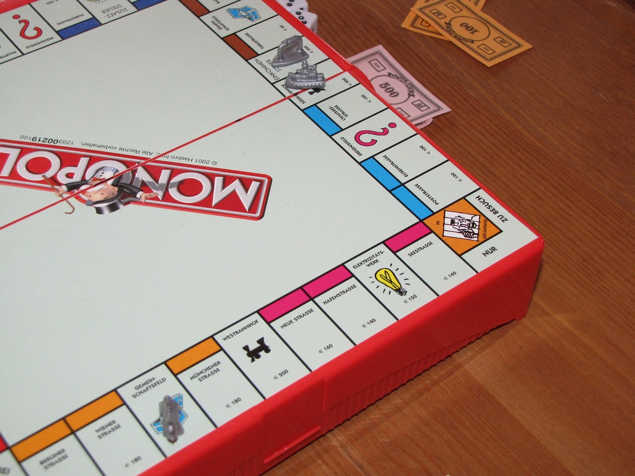 Auf dem Bild ist ein Ausschnitt eines Monopoly-Spielbretts mit Spieleld zu sehen