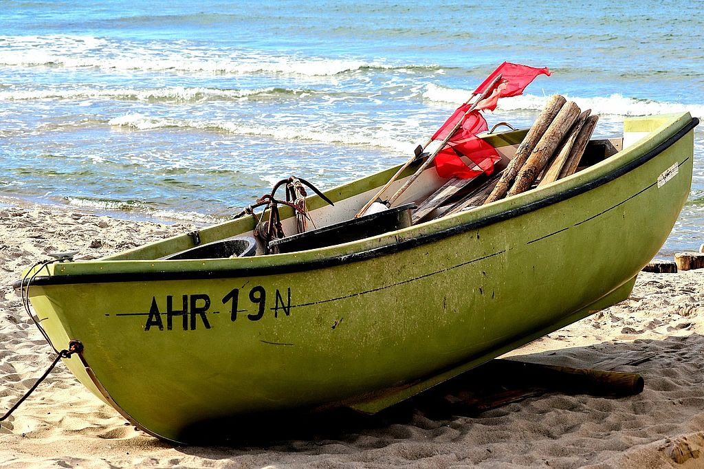 ein kleines Fischerboot in gelb liegt auf einem Ostseestrand